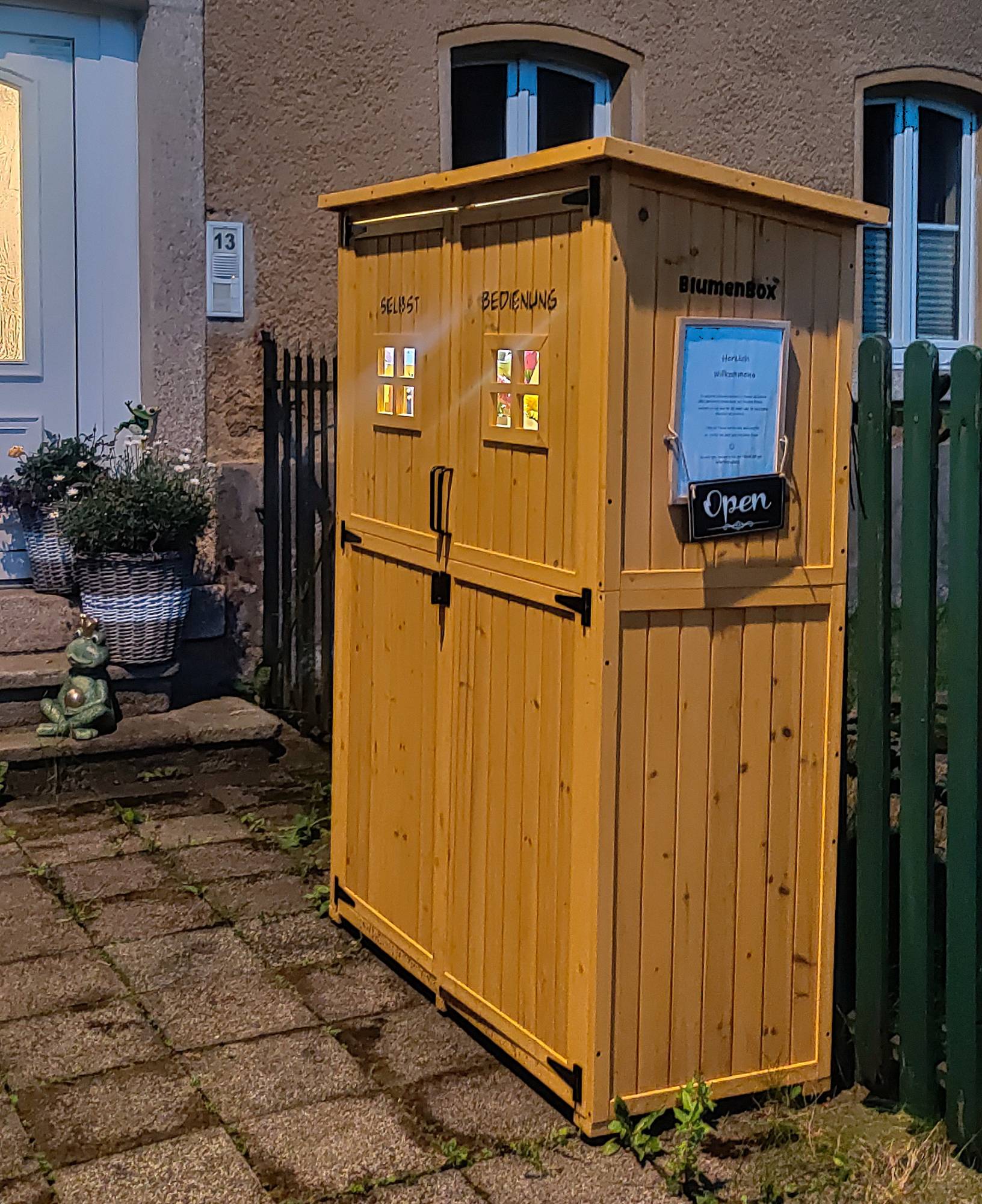 Der hölzerne Selbstbedienungsschrank der BlumenBox vor dem Haus Lauterbacher Straße 13 in Schreiersgrün